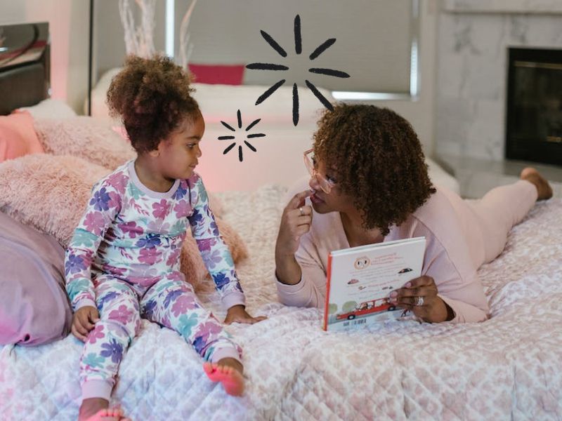 A mom reading a book to her young daughter at home
