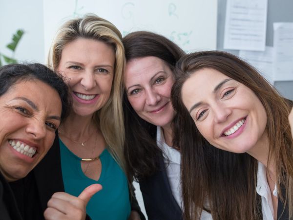 A group of 4 women looking at the camera and smiling