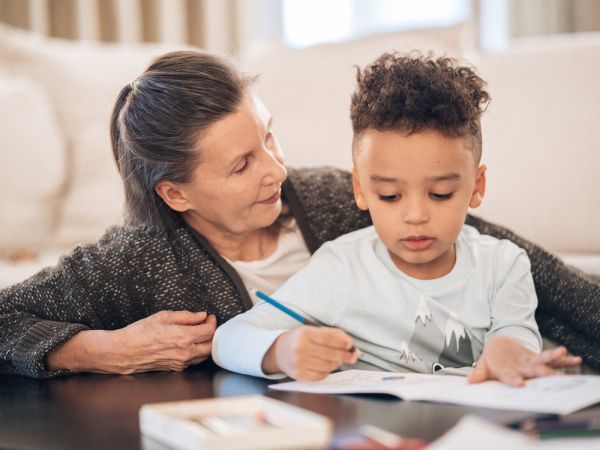 An older woman reading a book with a young child at home