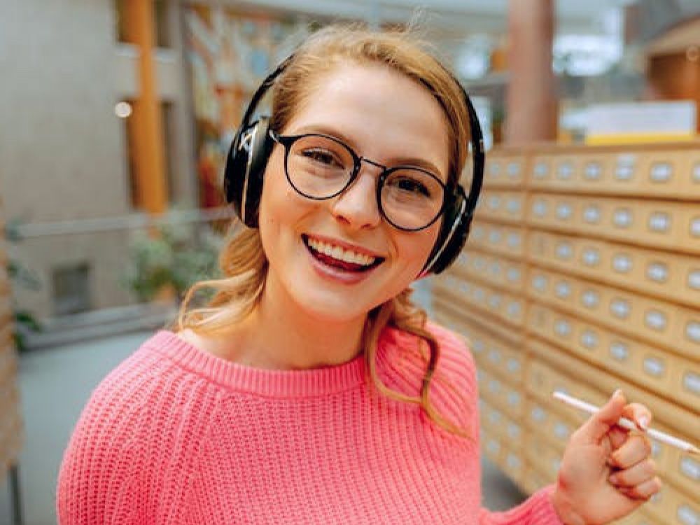 A teen girl in headphones smiling at the camera